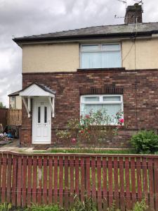 a brick house with a white door and a fence at semi-detach in Saint Helens