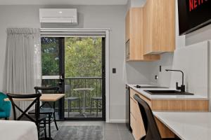 cocina con mesa y sillas y balcón en AVENUE MOTEL APARTMENTS en Toowoomba