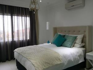 Un dormitorio con una cama con almohadas verdes y una ventana en 34 on Milkwood, en Durban