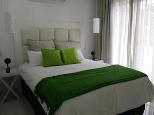 - une chambre avec un grand lit et des oreillers verts dans l'établissement 34 on Milkwood, à Durban