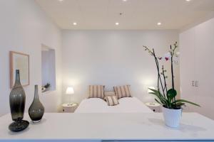a white bedroom with a white bed with two vases at Europahuset Apartments in Copenhagen