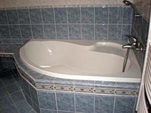 a bath tub in a bathroom with blue tiles at Penzion "Apartmány U Semušky" in Pernink
