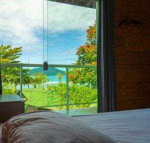 a bedroom with a large window with a view of the ocean at Green Haven Hostel in Ubatuba