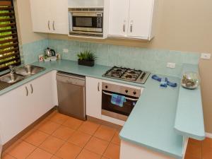 
a kitchen with a stove a sink and a microwave at Compass Point in Hamilton Island
