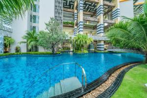 a swimming pool in front of a building at Riviera Jomtien by Daisy Pattaya in Jomtien Beach
