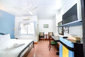 a bedroom with a bed and a desk with a tv at Pakdee House in Udon Thani