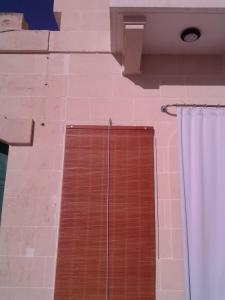 een douche met een houten deur en een gordijn bij Mgarr Waterfront Cosy Apartment 3 by Ghajnsielem Gozo in Mġarr