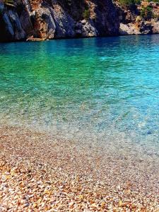 a beach with clear blue water and a rocky shore at Artemis House in Karpathos Town