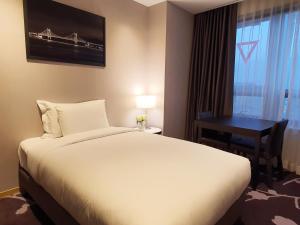 a hotel room with a bed, desk, and lamp at Avani Central Busan in Busan