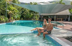 un hombre y una mujer sentados en una piscina en Oasis at Palm Cove en Palm Cove