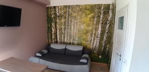 a room with a couch and a wall with a tree mural at OSADA POD LASEM in Andrychów