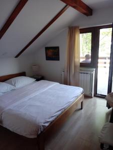 a bedroom with a white bed and a window at Guesthouse Marton in Jezerce