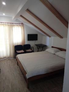 1 dormitorio con 1 cama, 2 sillas y TV en Guesthouse Marton, en Jezerce