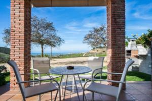 un patio con mesa, sillas y el océano en Casas Rurales El Mirador A, en Vejer de la Frontera