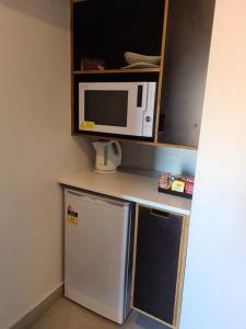 a small kitchen with a refrigerator and a microwave at Safari Lodge Motel in Tennant Creek