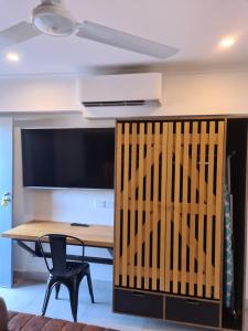 Elle comprend un bureau avec une table et une grande télévision. dans l'établissement Safari Lodge Motel, à Tennant Creek