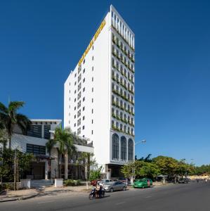 a tall white building with a yellow sign on it at Gold Plaza Hotel Da Nang in Danang