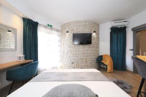 a room with two beds and a tv on a stone wall at Villa Dalmatino in Pakoštane