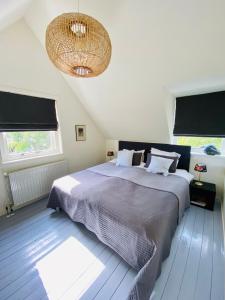 a bedroom with a large bed and a chandelier at Tiny House De Oude Berg in Bergen