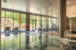 a large indoor pool with a waterfall in a room with windows at Vila Galé Collection Serra da Estrela in Manteigas
