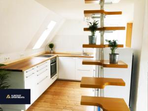 a kitchen with white cabinets and wooden shelves at Albstadt Apartments in Albstadt