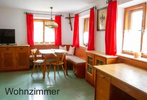 a kitchen with red curtains and a table and chairs at FeWo Berghex in Pinswang