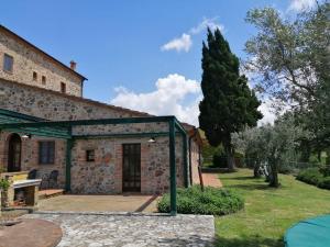 an external view of a stone building with a tree at Relais Poggio al Vento in Pomarance
