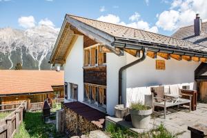 una casa con porche y montañas al fondo en Ferienwohnung Lenzerheide-Sporz, en Lenzerheide