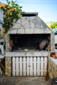 um forno de pedra com uma cerca branca em frente em Apartmani Milka Zadar em Zadar