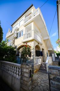 uma grande casa branca com uma varanda no topo em Apartmani Milka Zadar em Zadar