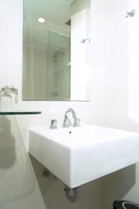 a white bathroom with a sink and a mirror at Lynn Hotel Serang in Serang