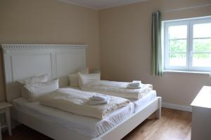 a white bedroom with two beds and a window at Ferienwohnung Boskop in Stade