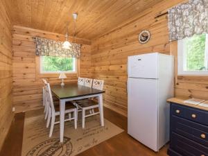 eine Küche mit einem Tisch und einem Kühlschrank in einem Blockhaus in der Unterkunft Holiday Home Kuusela by Interhome in Somerniemi