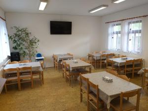 una sala con tavoli, sedie e TV a schermo piatto di U Pohody a Kovářská