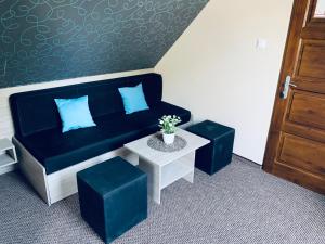 ein Wohnzimmer mit einem blauen Sofa und 2 Hockern in der Unterkunft Thermal Apartman in Makó
