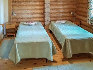 zwei Betten in einem Zimmer mit Holzwänden in der Unterkunft Holiday Home Männikkö by Interhome in Kammola