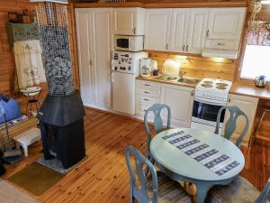 eine Küche mit einem Herd, einem Tisch, einem Tisch und Stühlen in der Unterkunft Holiday Home Eemeli by Interhome in Puomila