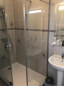 a shower with a glass door next to a sink at Crystal Hotel in Royan