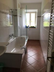ein Bad mit einer Badewanne, einem Waschbecken und einer Dusche in der Unterkunft Appartements im Forsthaus in Strobl