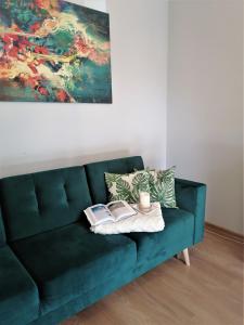 a green couch with two books and a painting at Apartament DobraNocka in Poronin