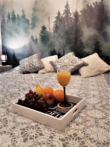 a tray of fruit and a glass of juice on a bed at Apartament DobraNocka in Poronin