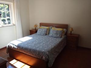 a bedroom with a bed with two night stands and a window at Residencial Ribeiro in Geres