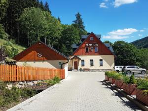 a building with an orange fence next to a driveway at Pension Pstruží in Pstruží