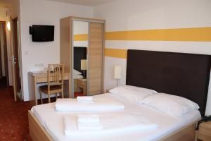 a bedroom with a bed with white sheets and a desk at Lenas Donau Hotel in Vienna