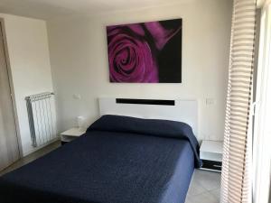 a bedroom with a blue bed and a painting on the wall at Aquarius Rome Apartments in Mostacciano