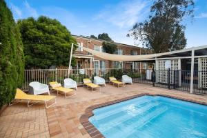 a swimming pool with lounge chairs and a swimming pool at The Horatio Motel Mudgee in Mudgee