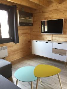 a living room with a tv and a table and a stool at CHALET LE HERISSON in Saint-Laurent-du-Jura