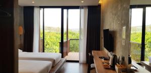 a hotel room with two beds and a desk with a television at Hug Jang Loei Garden & Resort in Ban Na Dan