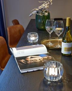 een boek op een tafel met glazen en een fles wijn bij The Guest Apartments - Uilenburg in Den Bosch