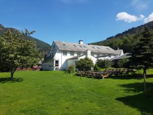 a large white house with picnic tables in a field at Folgefonn Gjestetun in Jondal